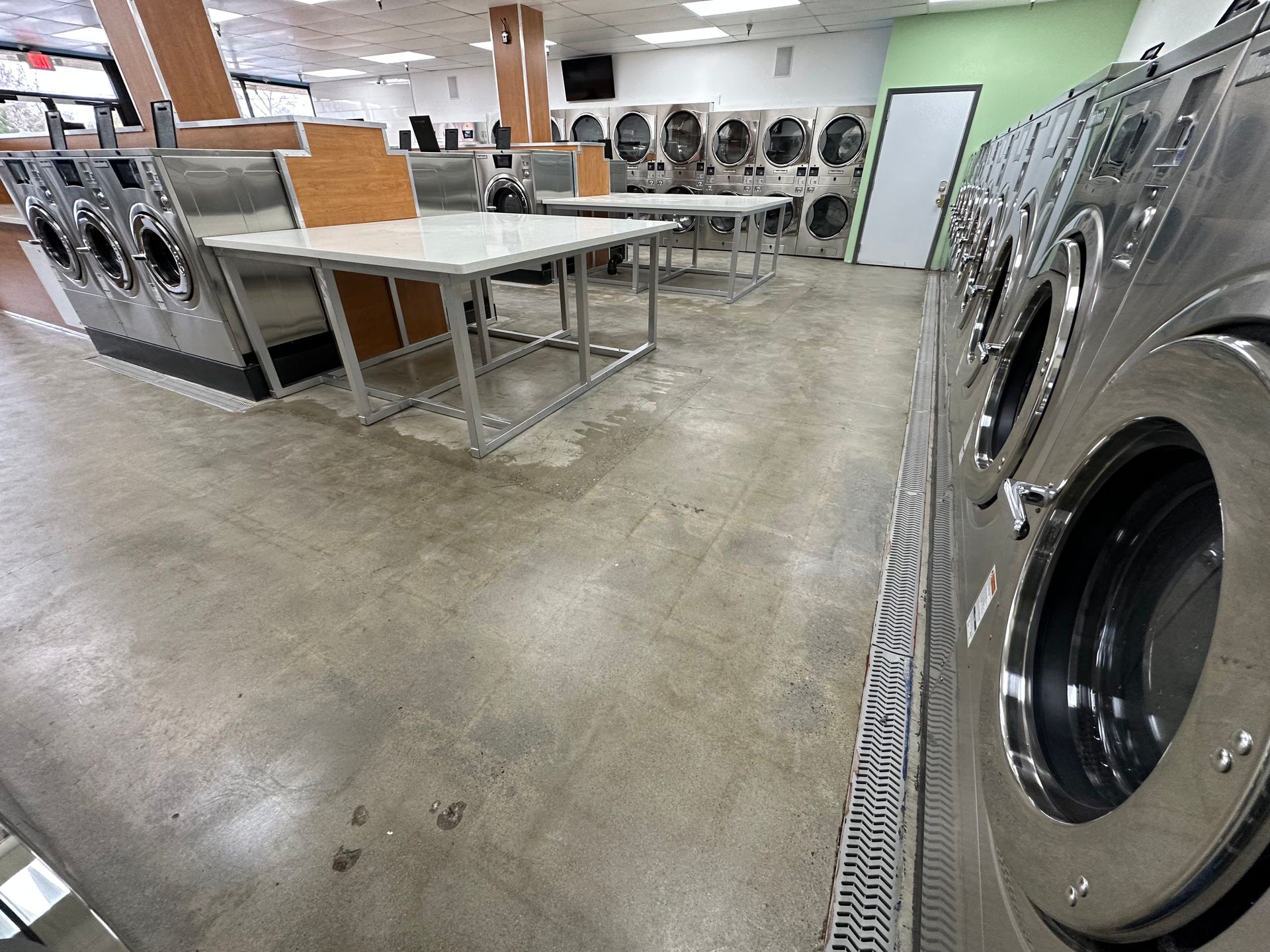 Two mirrored rows of front-load washers forming a long center aisle, each row framed by wood-toned end panels with small digital displays mounted above.